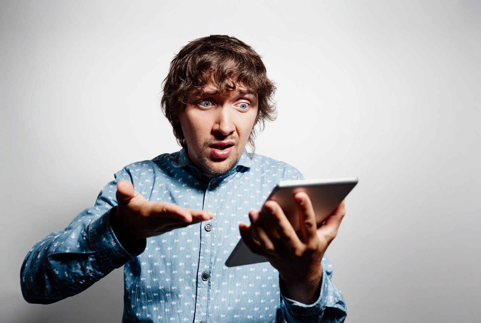 young man wearing blue shirt holding tablet scaled